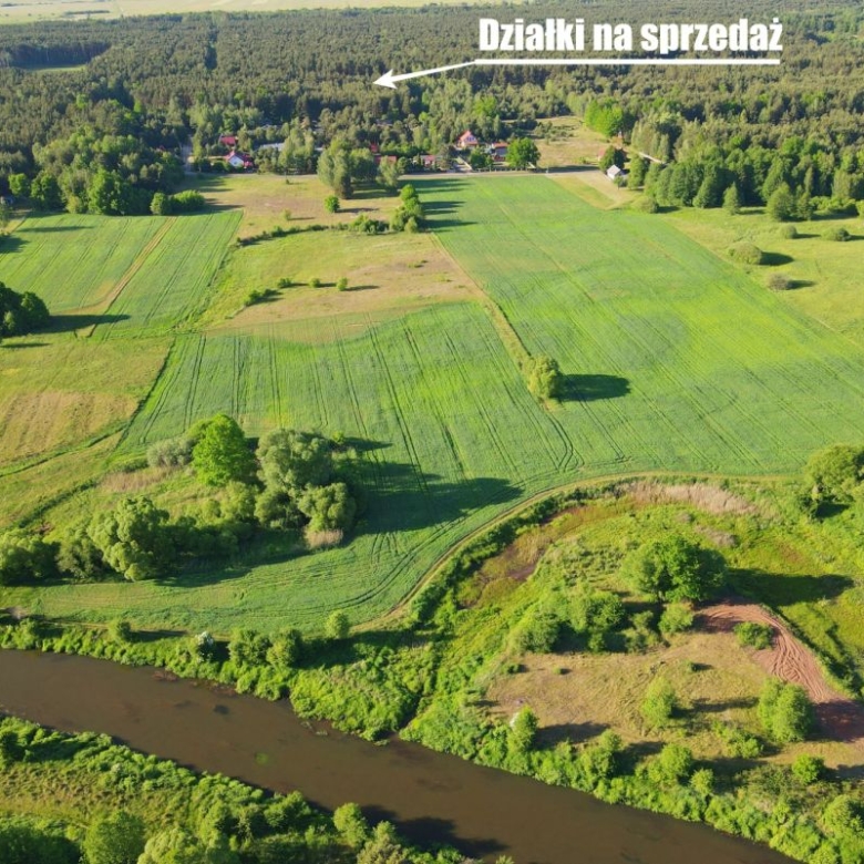 Aerial view of green farmland with rectangular plots for sale; text 'Działki na sprzedaż' across the top.