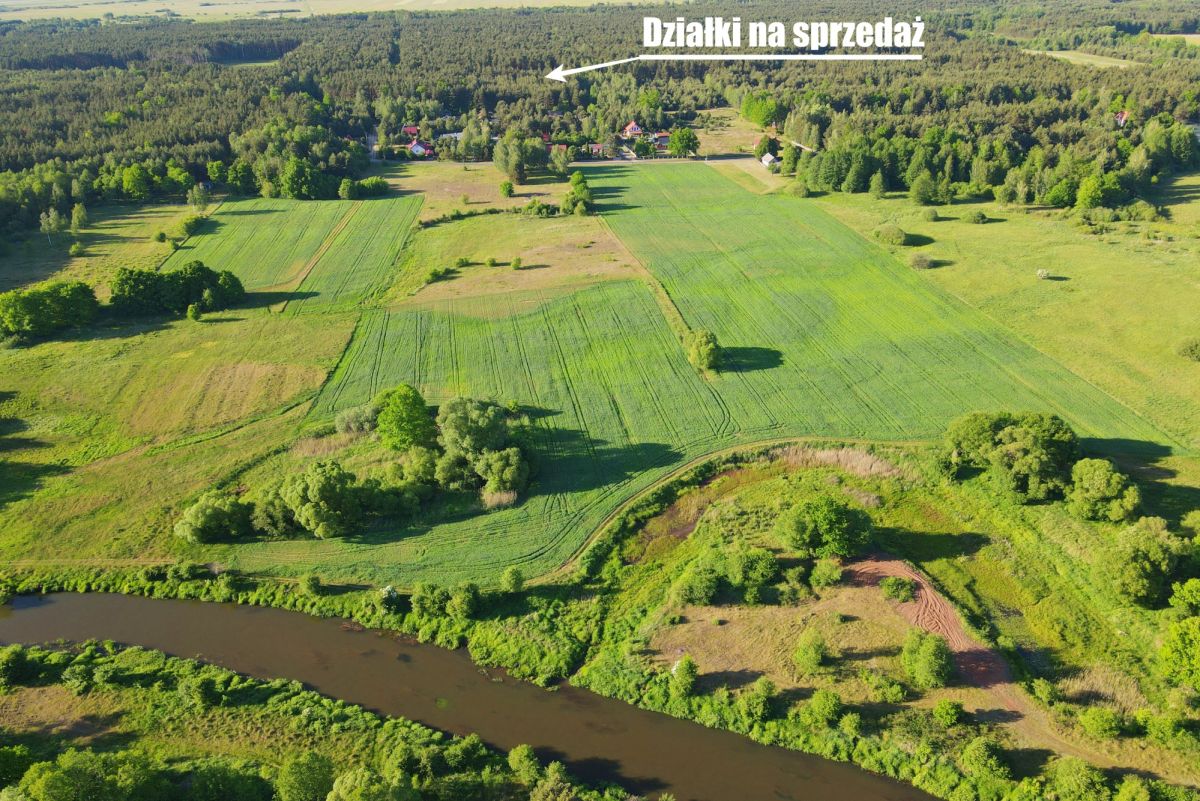 Aerial view of green farmland with rectangular plots for sale; text 'Działki na sprzedaż' across the top.