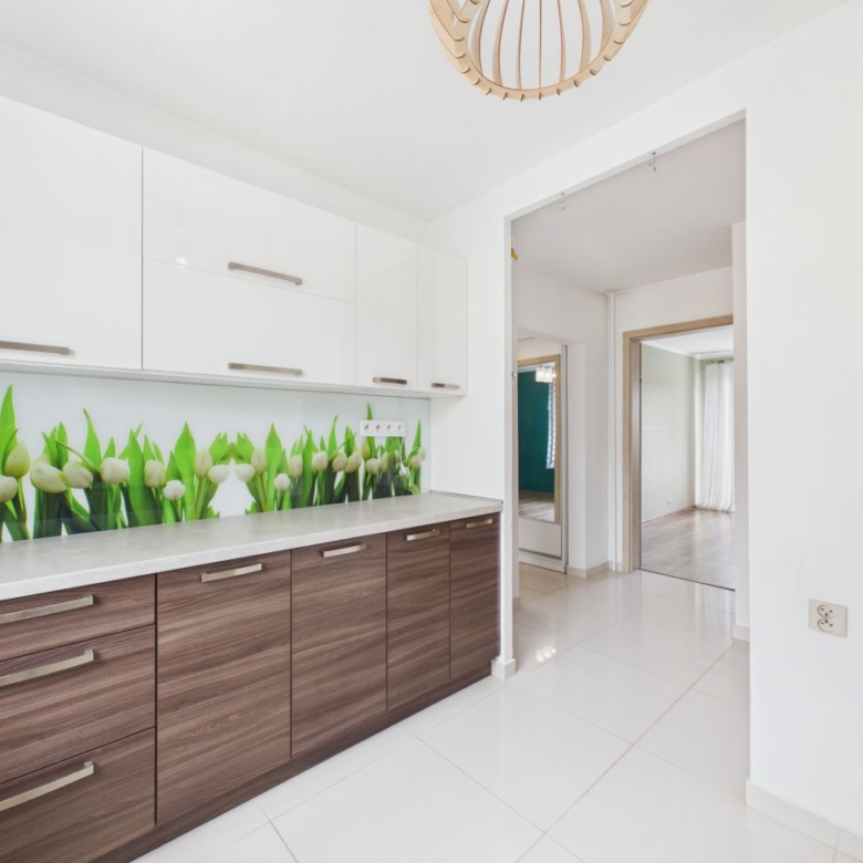 Modern kitchen with white upper cabinets, dark wood lower cabinets, and a tulip backsplash along a light countertop.
