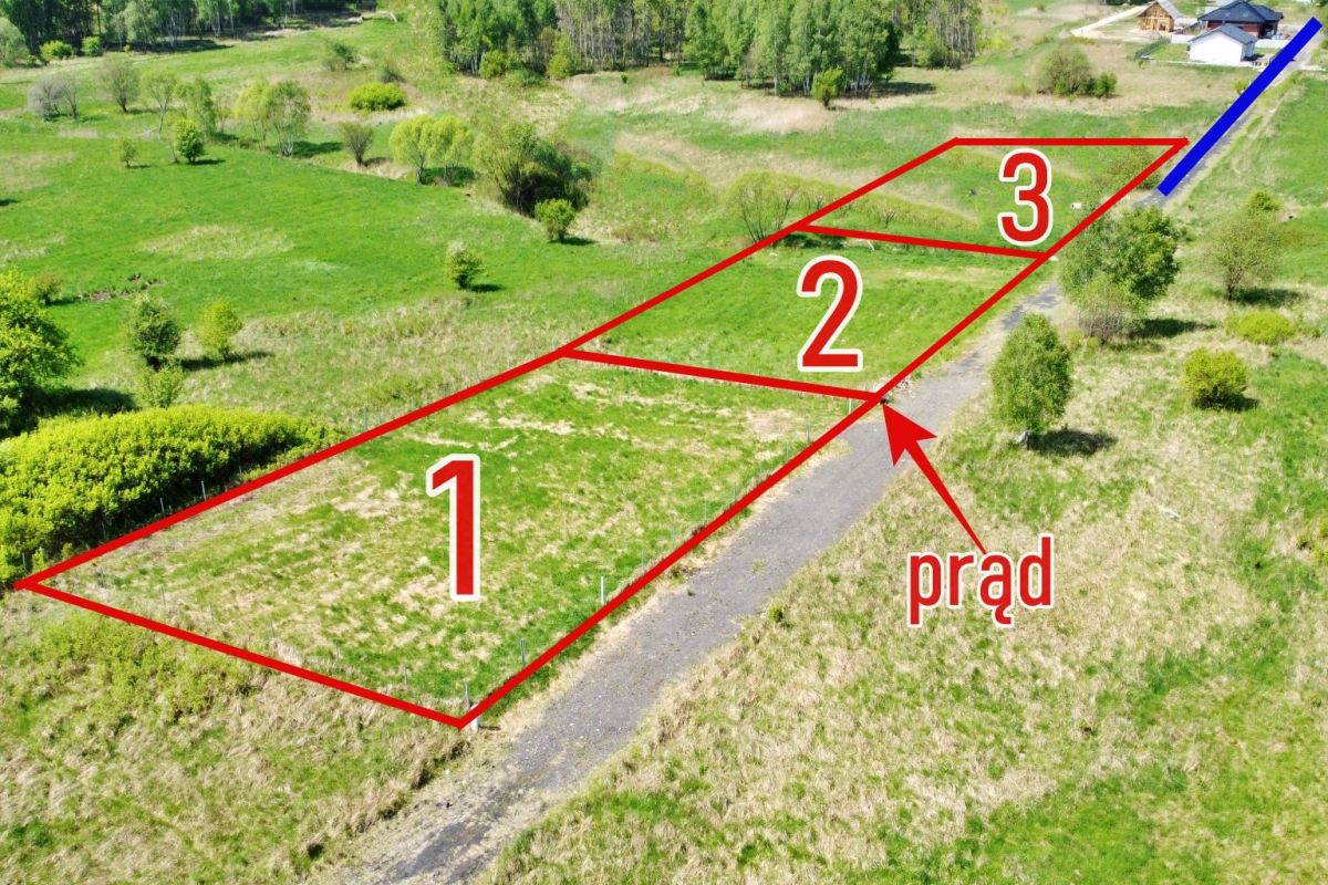 Aerial view of three red-outlined land plots labeled 1, 2, and 3 along a road, with a blue boundary and an arrow pointing to a utility line labeled 'prąd' (power).