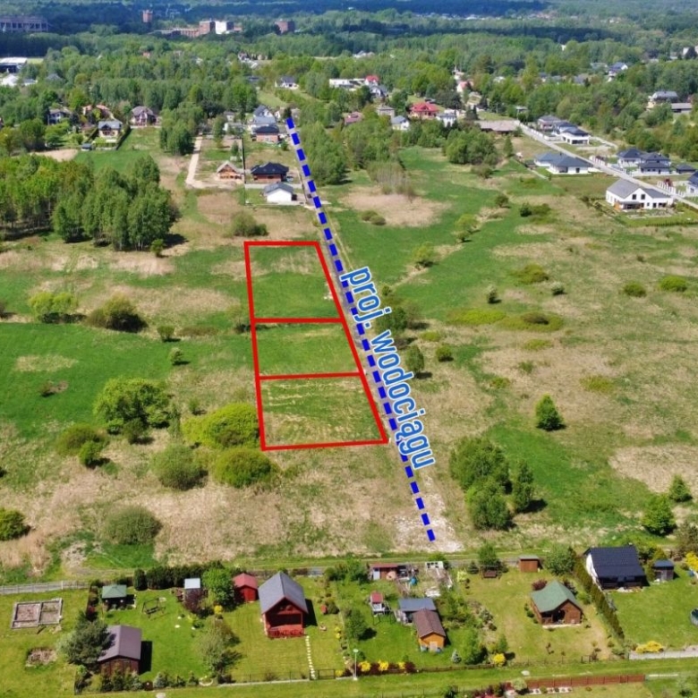 Aerial view of a vacant lot subdivision with three red-outlined parcels beside a diagonal blue road labeled 'Dr?giowa' or 'Wodog?dzi' in a rural neighborhood.