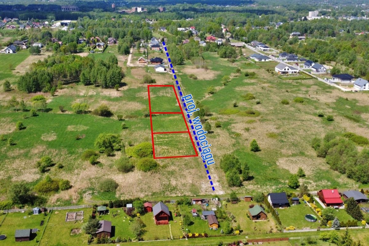 Aerial view of a vacant lot subdivision with three red-outlined parcels beside a diagonal blue road labeled 'Dr?giowa' or 'Wodog?dzi' in a rural neighborhood.