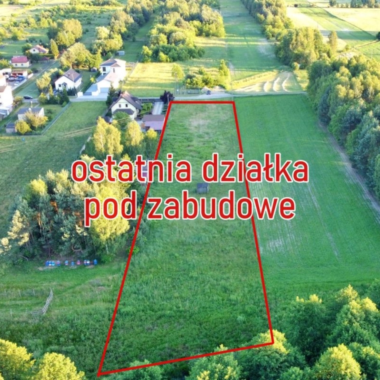 Aerial view of a triangular plot outlined in red in a green field, with nearby houses and the Polish text 'ostatnia działka pod zabudowę' overlays