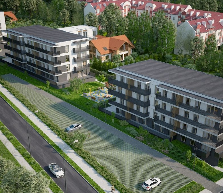 Aerial view of a modern apartment complex with three multi-story buildings, green spaces, and a tree-lined street with parked cars nearby.”] ,
