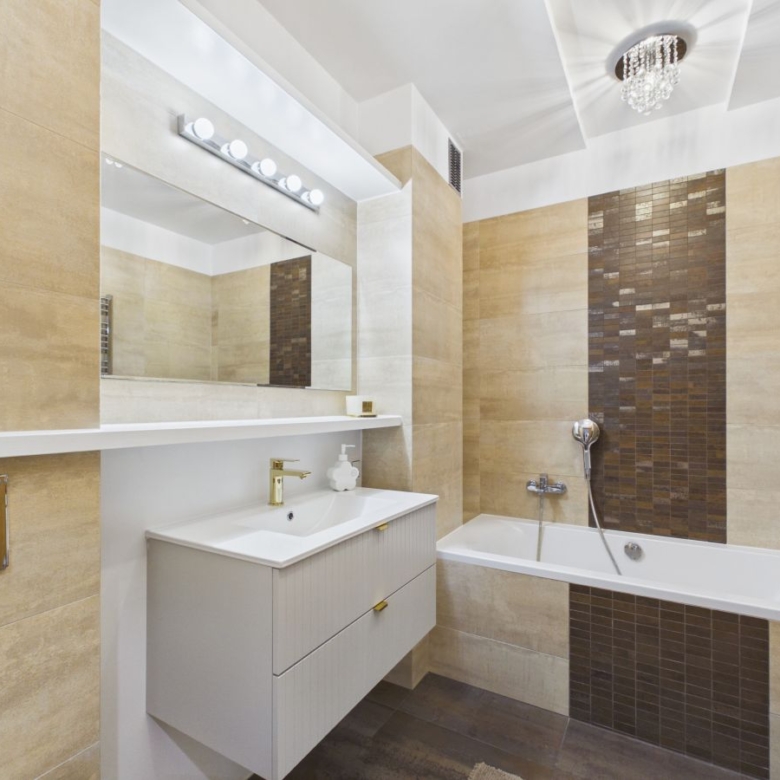 Modern bathroom with a white vanity, sink, and large mirror beneath a row of lights.