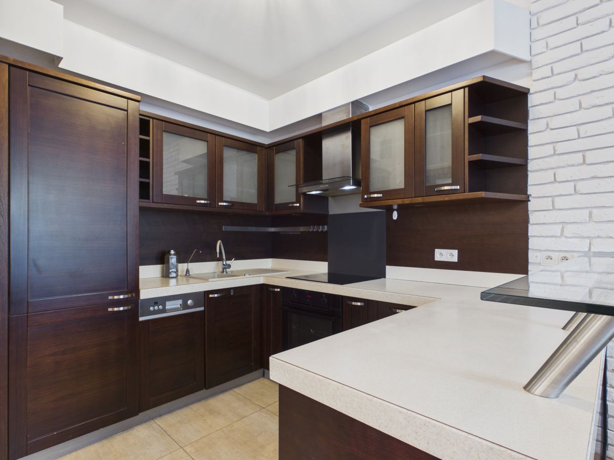 U-shaped kitchen with dark wood cabinets, white countertops, and stainless steel appliances.