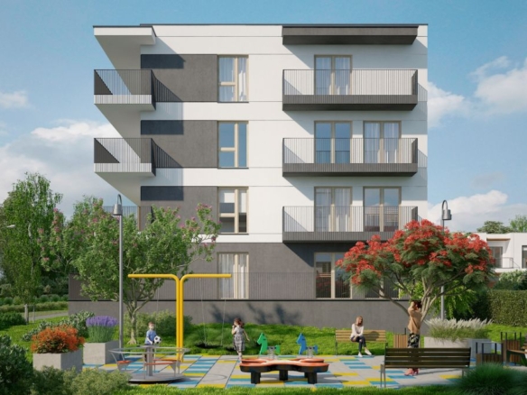 Modern four-story apartment building with balconies overlooking a sunny playground with colorful safety flooring and benches in the foreground.