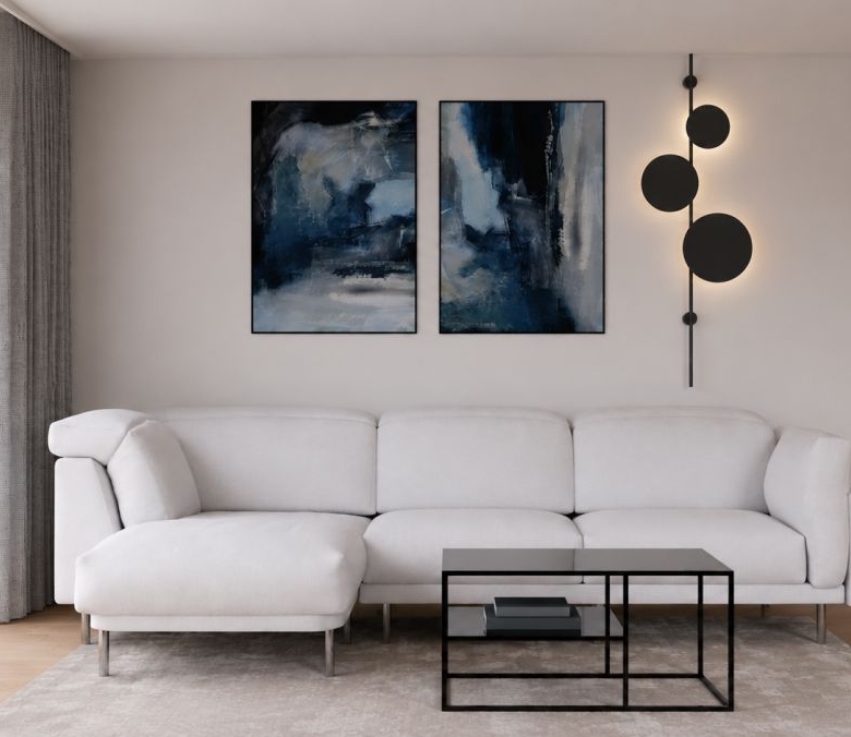 Modern living room with a white sectional sofa, two abstract blue paintings, and a black metal coffee table