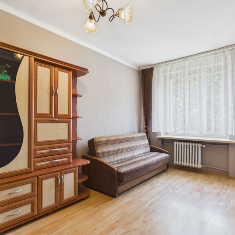 Living room with a large wooden cabinet, brown striped sofa, and a window with lace curtains.