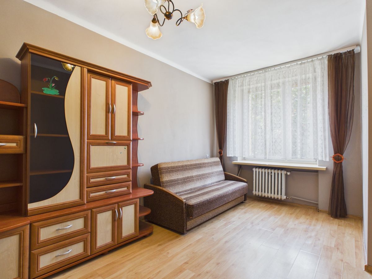 Living room with a large wooden cabinet, brown striped sofa, and a window with lace curtains.