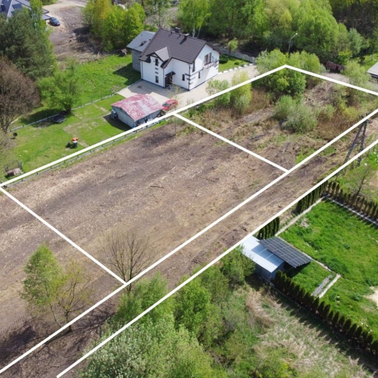 Aerial view of a residential plot divided into four outlined parcels, showing cleared and grassy lots with surrounding houses and trees.