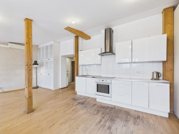 Open-plan kitchen with white cabinetry, built-in oven and stove, stainless range hood, and exposed wooden posts.