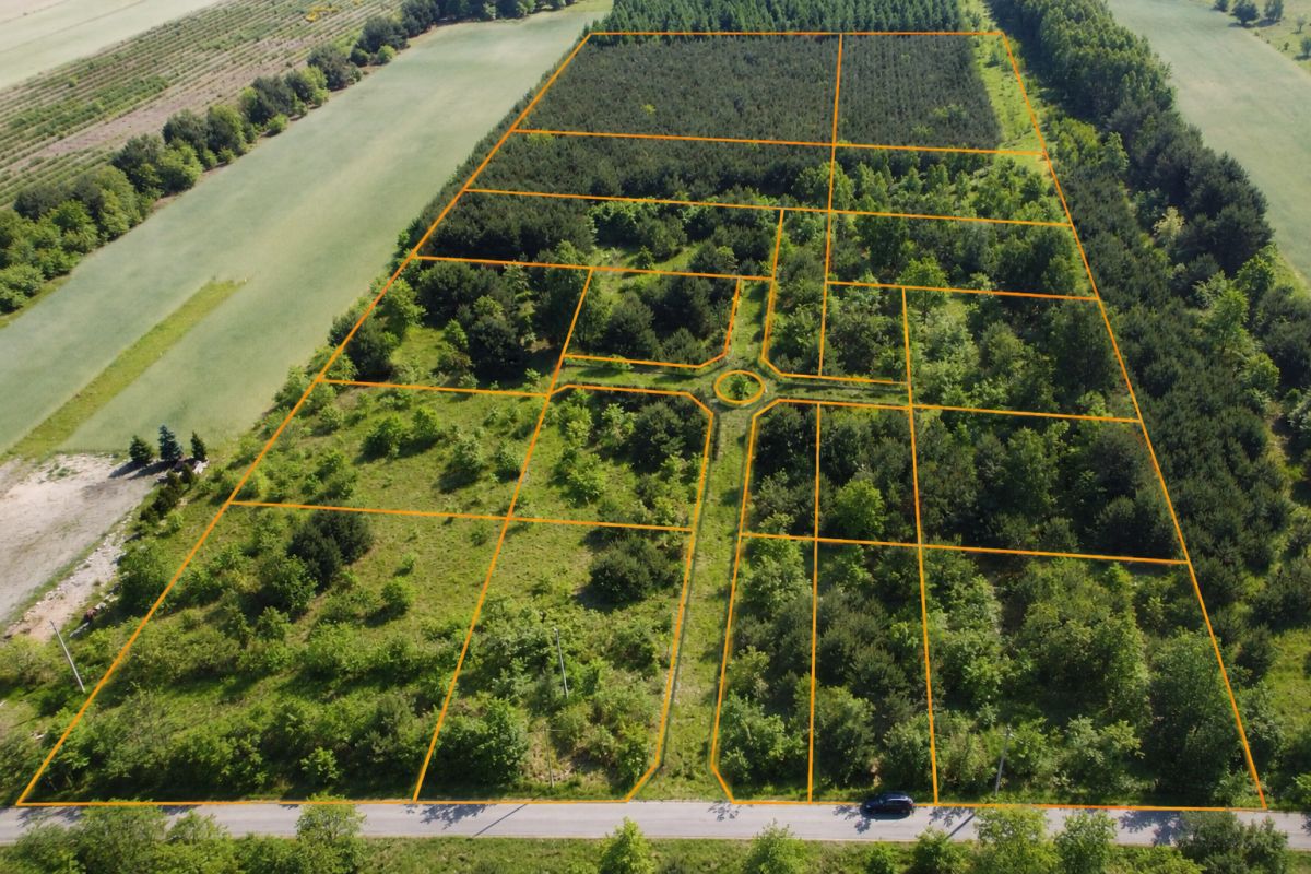 Aerial view of a wooded subdivision with orange boundary lines dividing multiple rectangular lots around a circular cul-de-sac at the center.