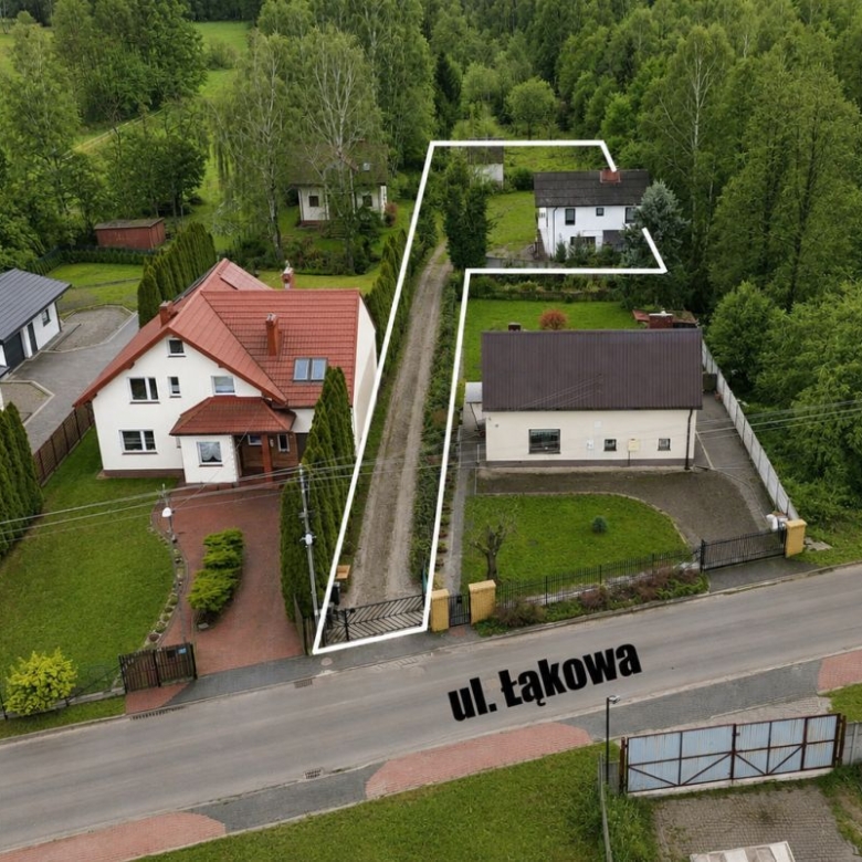 Aerial view of a residential street with a long, narrow property outlined in white, extending from the front near ul. Łąkowa into a rear garden area behind neighboring houses.