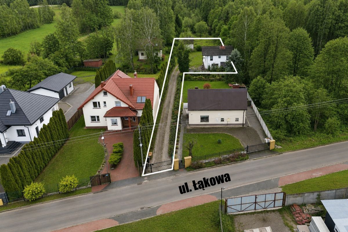 Aerial view of a residential street with a long, narrow property outlined in white, extending from the front near ul. Łąkowa into a rear garden area behind neighboring houses.