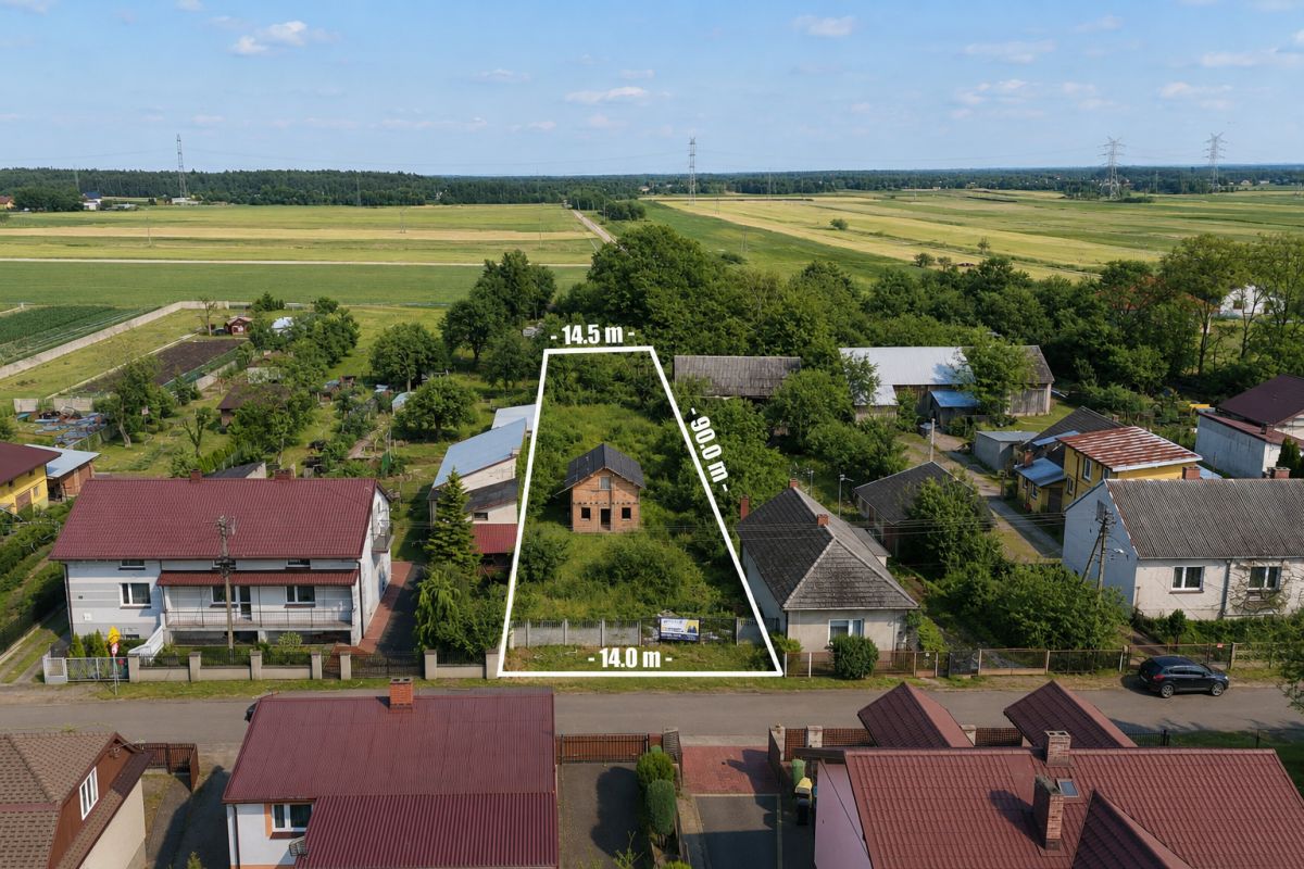Aerial view of a triangular vacant lot outlined in white between houses, with dimensions 14.0 m base, 14.5 m top, and 29.0 m side, in a village setting.