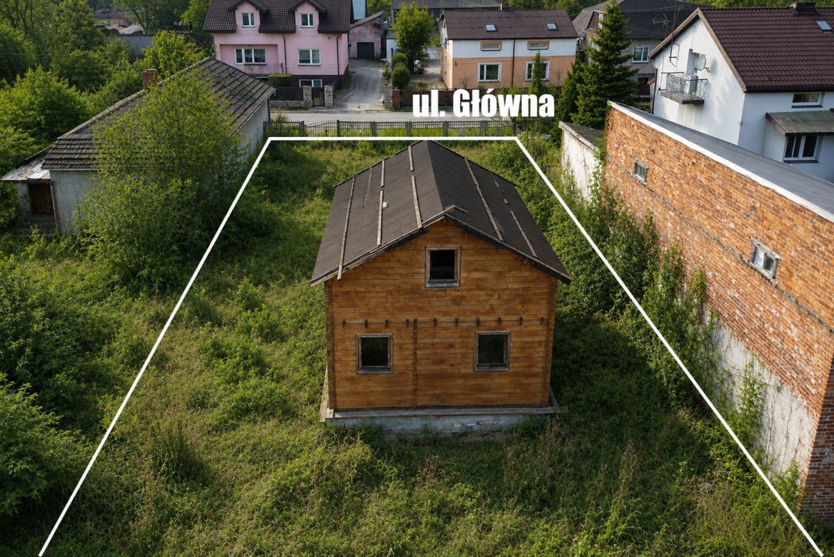 Wooden house in overgrown lot outlined as a plot, with a street label 'ul Główna' overhead in a residential area