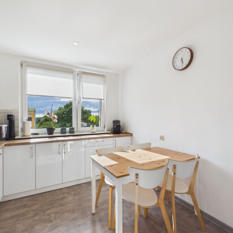 Bright white kitchen with wooden countertops, a rectangular dining table and four chairs by the window.