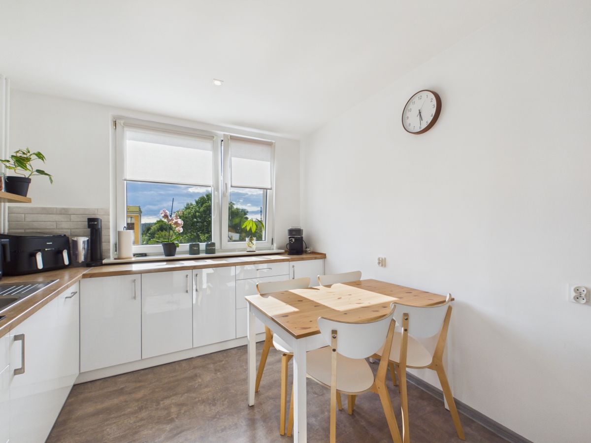 Bright white kitchen with wooden countertops, a rectangular dining table and four chairs by the window.