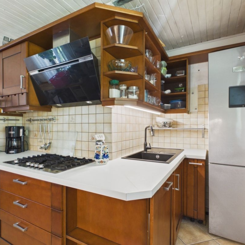 Cozy kitchen with dark wood cabinets, stainless steel gas stove, and open shelves above a white counter.