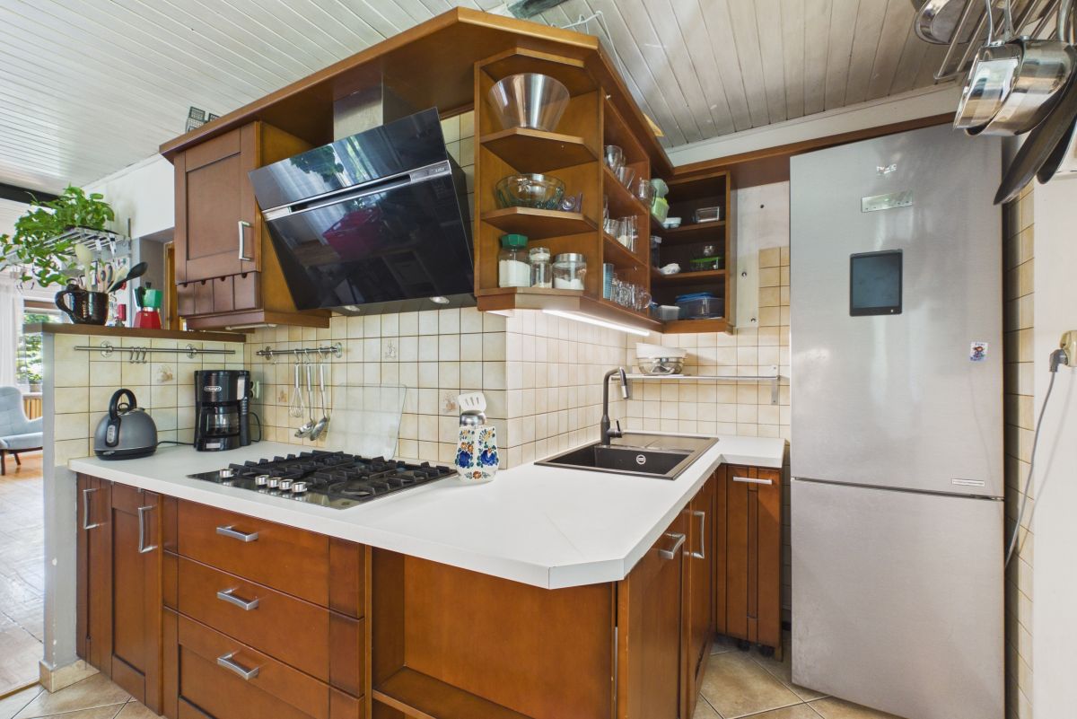 Cozy kitchen with dark wood cabinets, stainless steel gas stove, and open shelves above a white counter.
