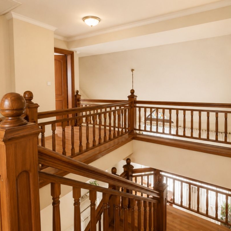 Wooden staircase and railings in a bright hallway, with decorative newel posts on the landing area.