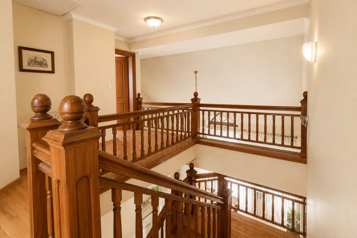 Wooden staircase and railings in a bright hallway, with decorative newel posts on the landing area.