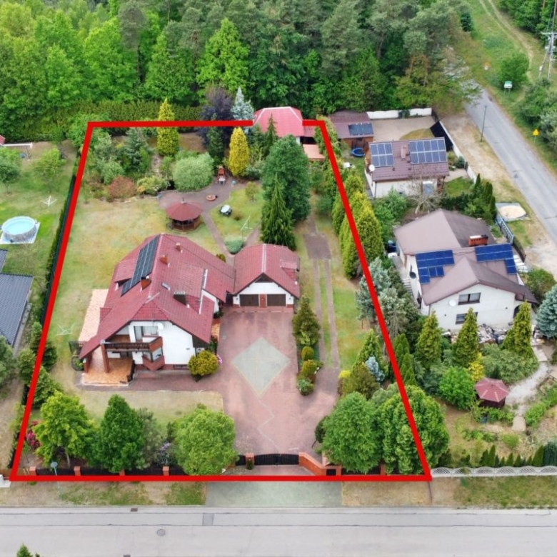 Aerial view of a residential property with a red boundary outline enclosing a two-story house, driveway, garden, and trees.
