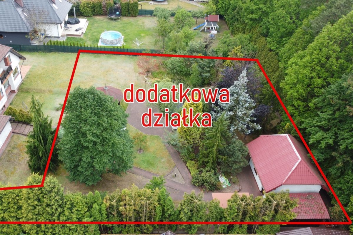Aerial view of a residential garden outlined in red, labeled 'dodatkowa działka,' with trees, paths and a small building nearby.