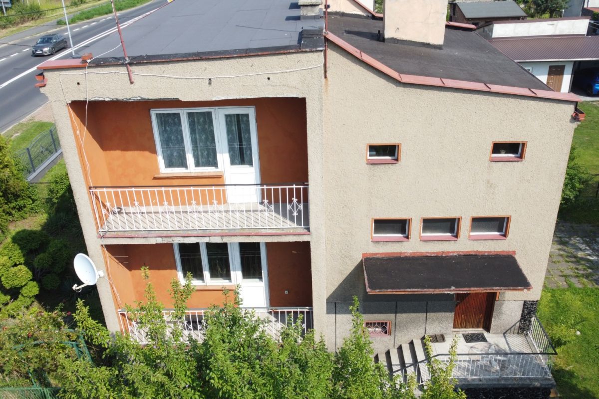 Aerial view of a two-story beige stucco building with orange inner walls, white balcony railings, and a white door on the upper balcony.