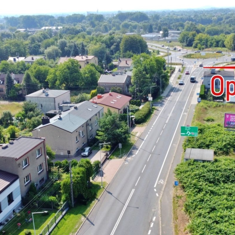 Aerial view of a residential street with cars, with a red arrow pointing to the word 'Opole' indicating the city.