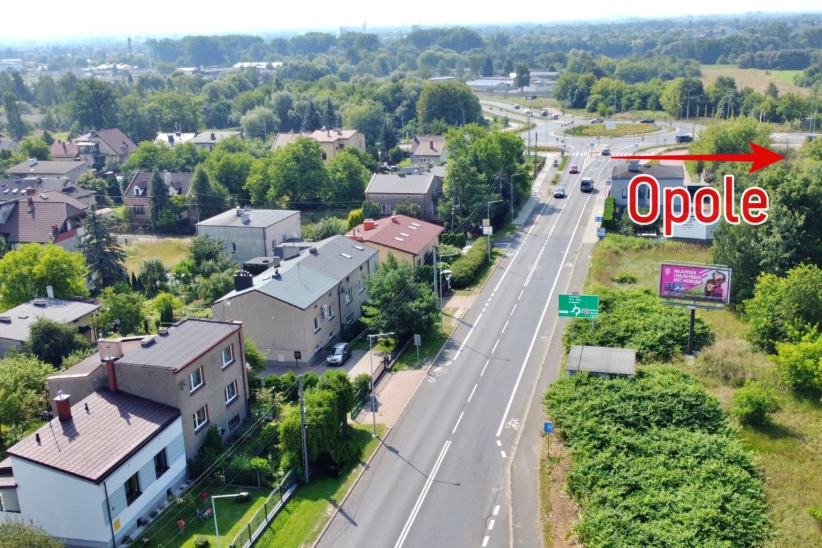 Aerial view of a residential street with cars, with a red arrow pointing to the word 'Opole' indicating the city.