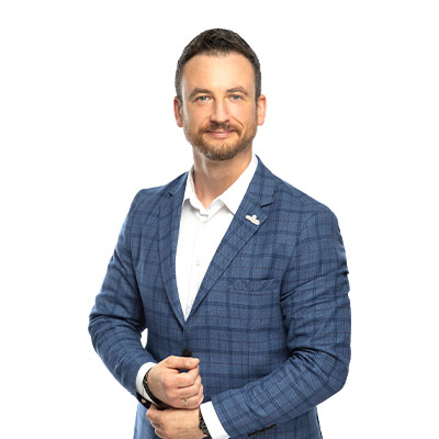 Professional headshot of a man in a blue checked blazer and white shirt, smiling at the camera.